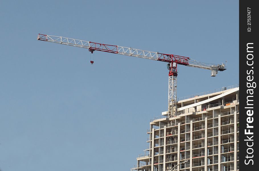 Climbing lifting crane on a building under construction. Against a blue sky. Climbing lifting crane on a building under construction. Against a blue sky.
