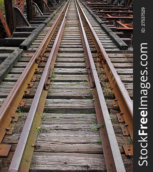 Duel set of rusty abandoned railroad tracks going across a bridge. Duel set of rusty abandoned railroad tracks going across a bridge.