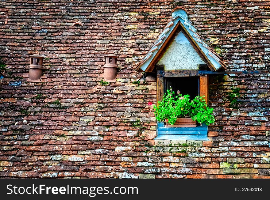 Old orange vintage retro brick roof with window and flowers. Old orange vintage retro brick roof with window and flowers
