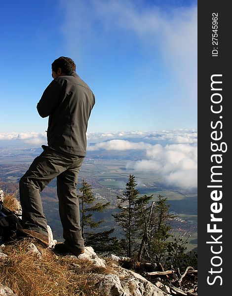 This image presents a young man admiring the view from the top of the mountain in Piatra Craiului, Romania .