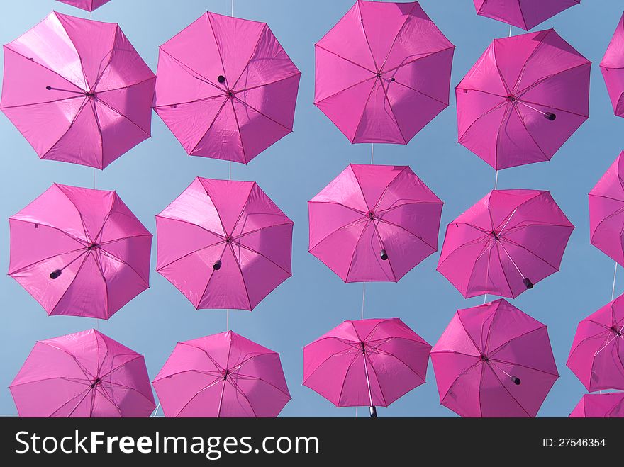 Pink umbrellas stacked above the street advertising purposes