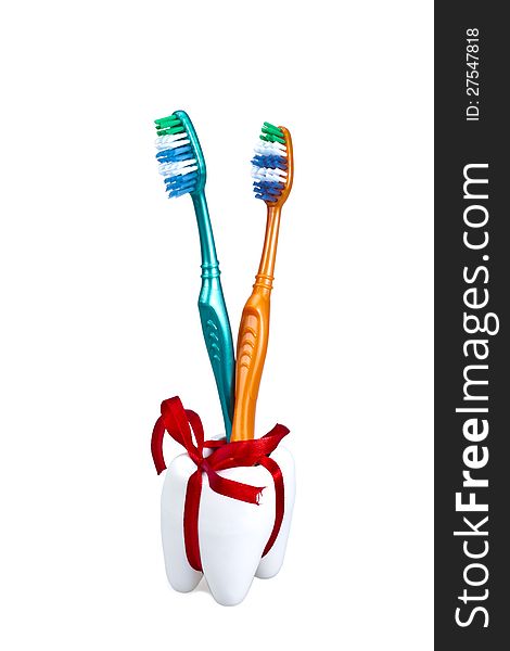 Toothbrushes with a holder in shape of a tooth with a red gift ribbon. Toothbrushes with a holder in shape of a tooth with a red gift ribbon