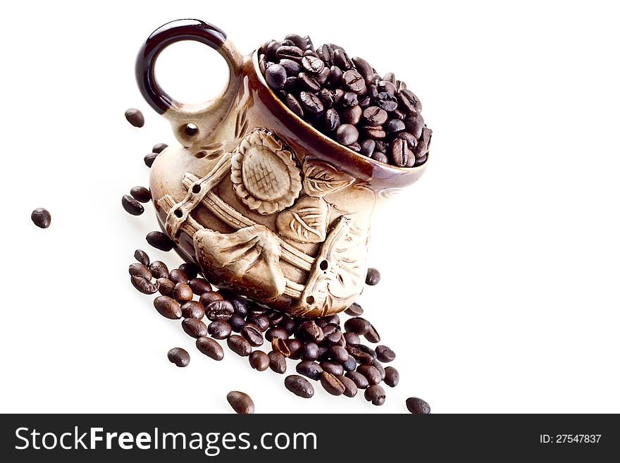 A hand made cup with coffee beans isolated on white.