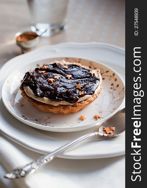 Christmas Tartlet Decorated with Chocolate, White Cream and Small Gold Asterisks on a White Plate. Christmas Tartlet Decorated with Chocolate, White Cream and Small Gold Asterisks on a White Plate