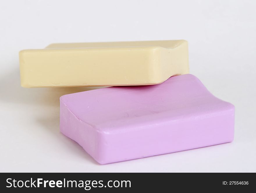 Two new pieces of soap, pink and yellow, on a white background