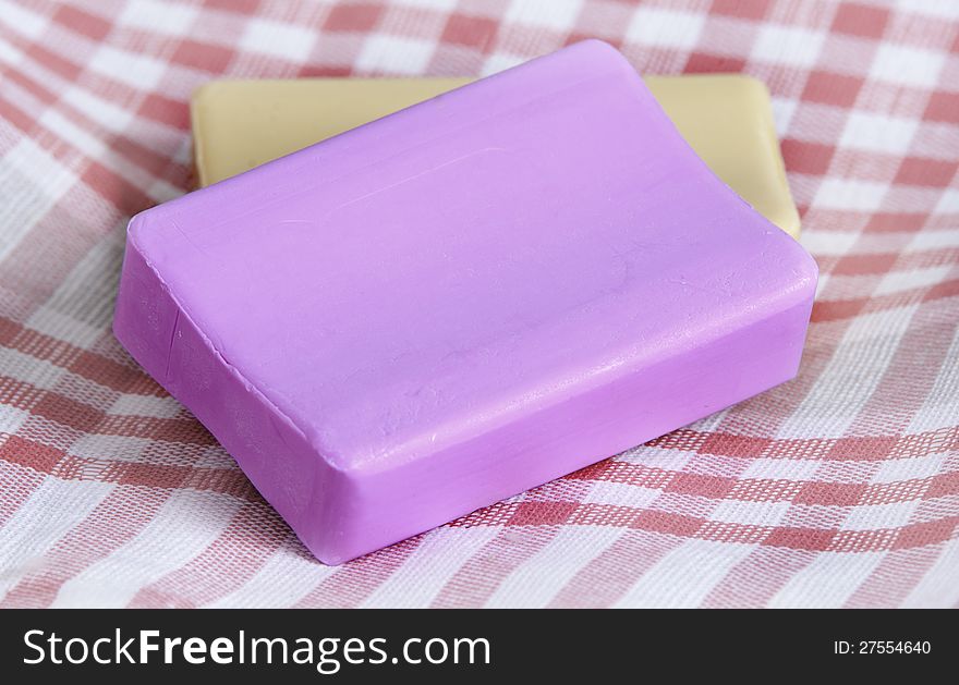 Two new pieces of soap, pink and yellow, on a checkered napkin