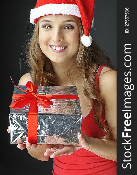 Christmas smiling girl holds gift wearing Santa hat. Christmas smiling girl holds gift wearing Santa hat.
