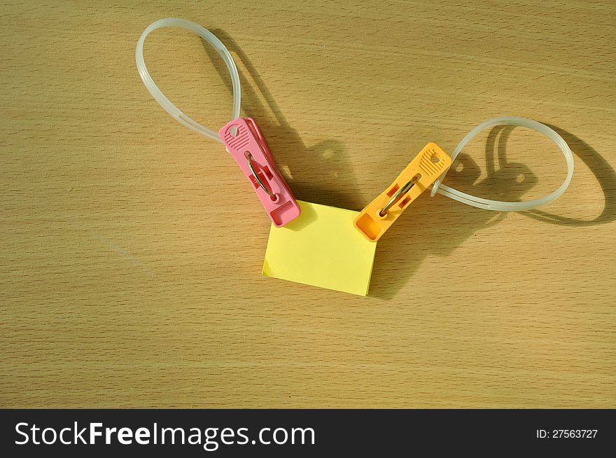 Yellow reminder note papers with color clothespins design on wooden texture. Yellow reminder note papers with color clothespins design on wooden texture