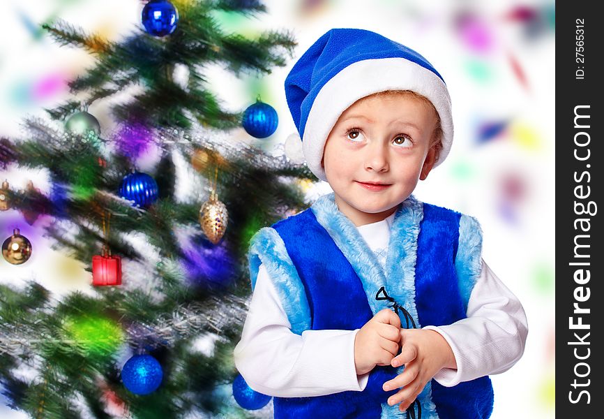 Boy in a cap of Santa Claus on Christmas tree background