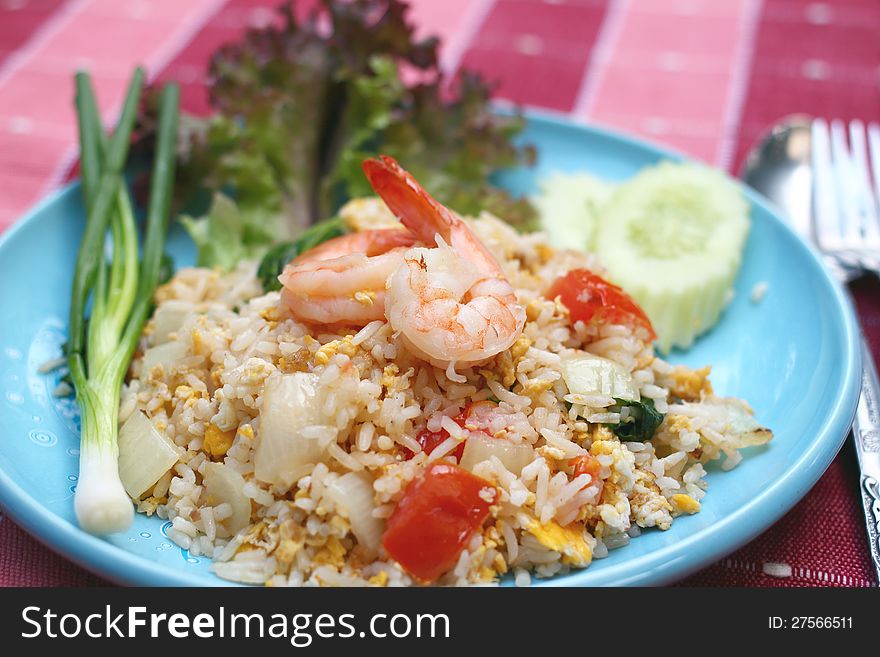 Shrimp fried rice with eggs, onion and tomato on blue plate