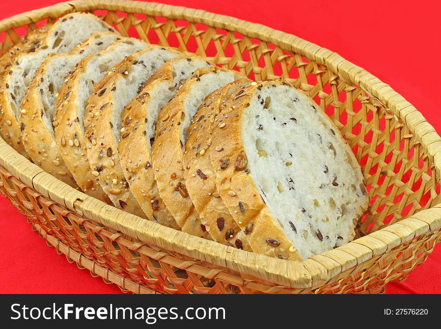 Fresh white bread pieces with whole seeds in a wicker basket on a red napkin. Fresh white bread pieces with whole seeds in a wicker basket on a red napkin