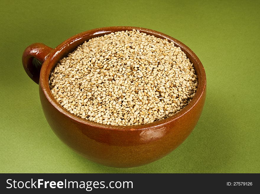 Dry sesame in ceramic bowl on green background. Dry sesame in ceramic bowl on green background