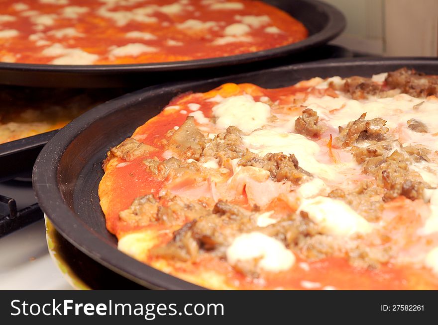 Freshly baked pizza with sausage and mozzarella in baking tin. Freshly baked pizza with sausage and mozzarella in baking tin