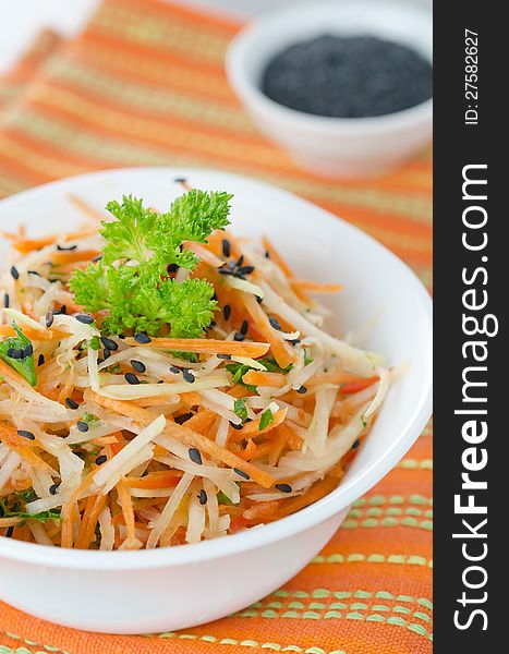 A bowl of salad with cauliflower, carrots and peppers, sprinkled with black sesame. A bowl of salad with cauliflower, carrots and peppers, sprinkled with black sesame