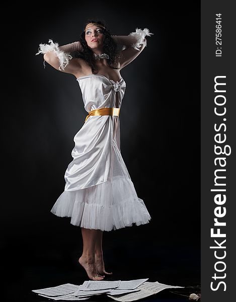 Portrait of a pretty girl in a white dress as if hovering over the notes on a black background in the studio. Portrait of a pretty girl in a white dress as if hovering over the notes on a black background in the studio