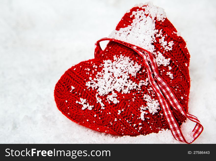 Red woolen heart left in snow