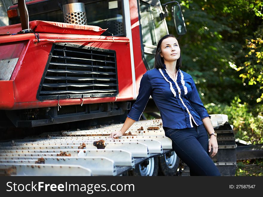 Attractive girl about caterpillar tractor in summer day