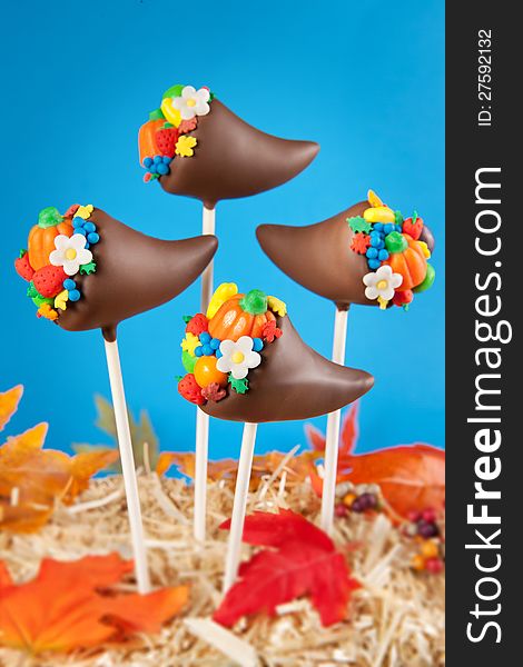 Thanksgiving cake pops. Mini cakes shaped like cornucopias, dipped in chocolate and decorated with candy, sprinkles, fondant fruits and flowers. Thanksgiving cake pops. Mini cakes shaped like cornucopias, dipped in chocolate and decorated with candy, sprinkles, fondant fruits and flowers