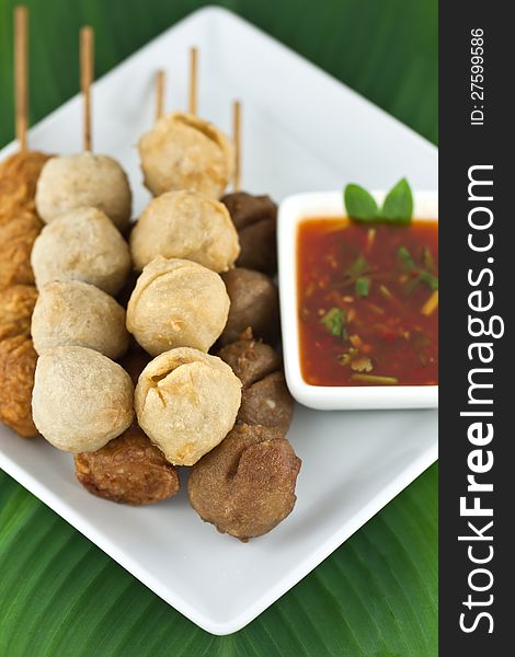 Fried meatballs skewers with sauce put on white dish