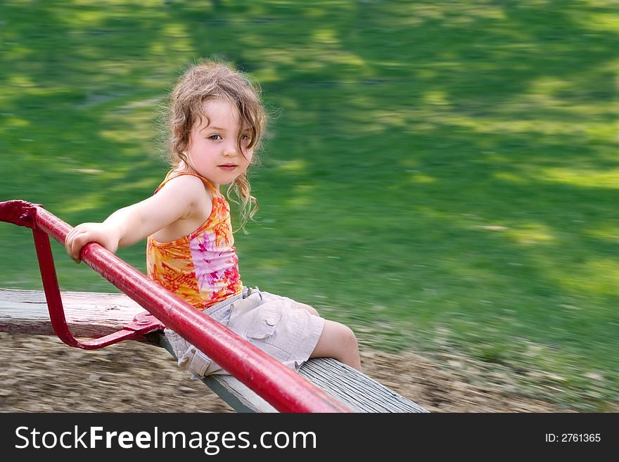 A little girl spinning on a merry-go-round. A little girl spinning on a merry-go-round