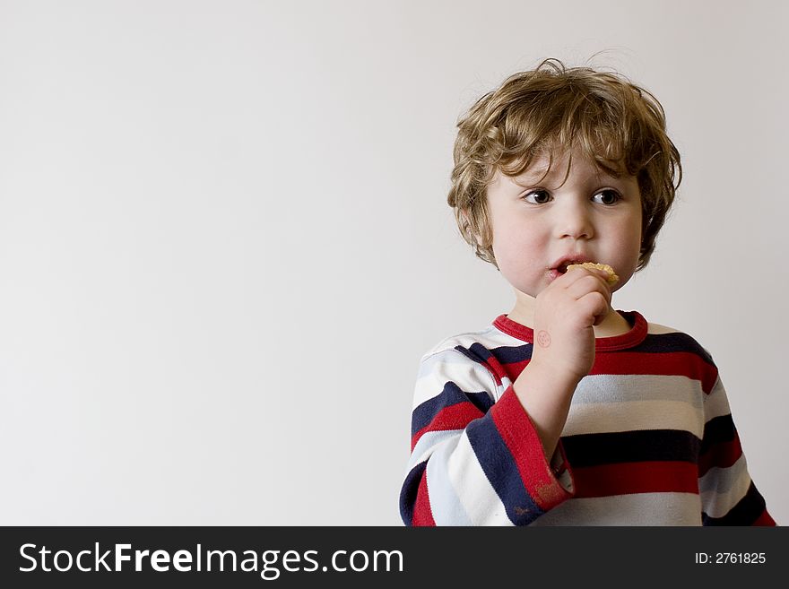 Child in striped shirt eating a cookie or biscuit. Child in striped shirt eating a cookie or biscuit