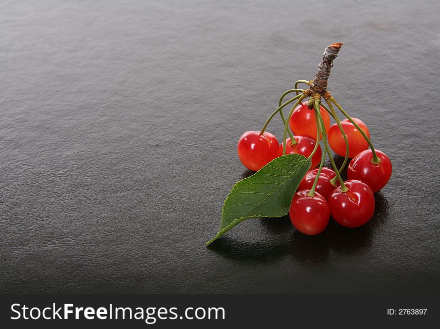 Bright colorful fresh cherries over a black texteure