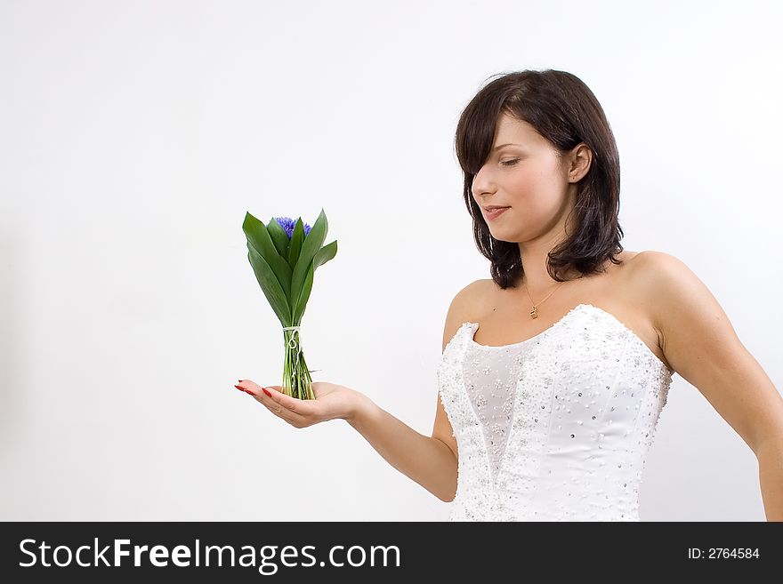 Beautiful white woman in a wedding dress isolated on a white background posing with flowers. Beautiful white woman in a wedding dress isolated on a white background posing with flowers