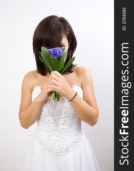 Beautiful white woman in a wedding dress isolated on a white background posing with flowers. Beautiful white woman in a wedding dress isolated on a white background posing with flowers
