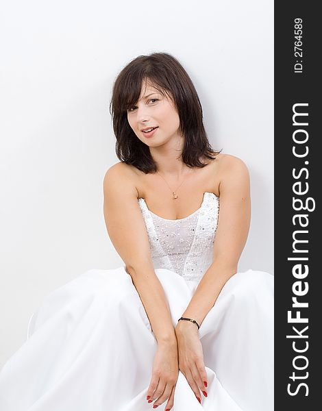 Beautiful white woman in a wedding dress isolated on a white background relaxing. Beautiful white woman in a wedding dress isolated on a white background relaxing