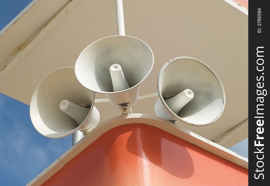 Three white megaphones mounted on a white and orange tower. Three white megaphones mounted on a white and orange tower