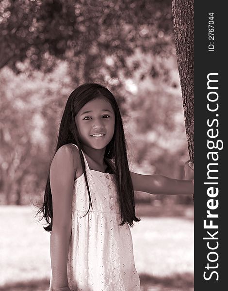 Young girl standing by tree,sepia toned. Young girl standing by tree,sepia toned