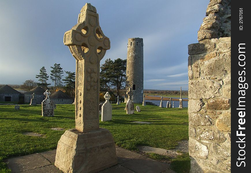 View of Celtic cross and old cemetry and round tower ruins dating to 10th century Ireland