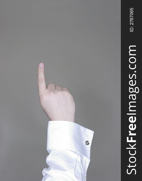 An arm raised with an a finger pointing up while wearing business clothes. An arm raised with an a finger pointing up while wearing business clothes