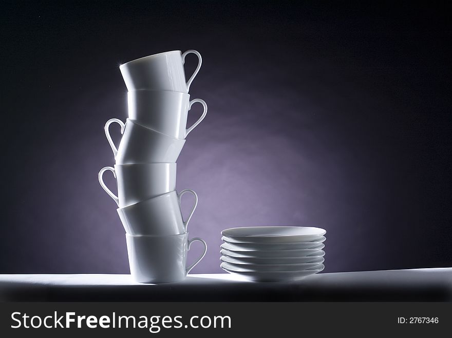 A pile of cups in a s shape whit some dishes in a black background, studio image composition. A pile of cups in a s shape whit some dishes in a black background, studio image composition