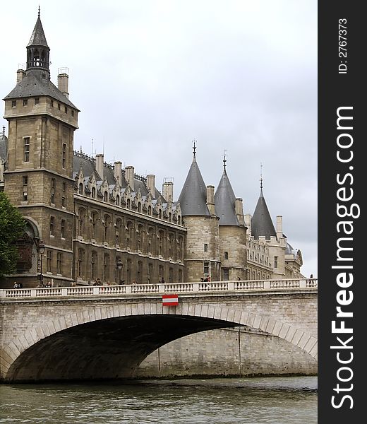 View of the Conciergerie and bridge from the Seine River in Paris, France, in gray misty light. View of the Conciergerie and bridge from the Seine River in Paris, France, in gray misty light.