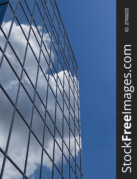 Building against a solid blue sky, reflecting sky and clouds. Building against a solid blue sky, reflecting sky and clouds