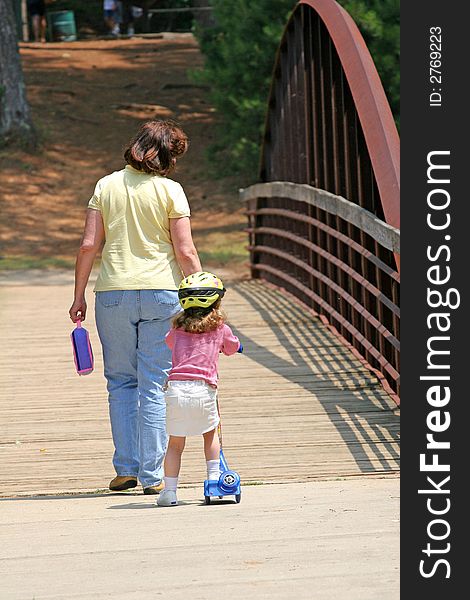 A mother and girl on skates crossing a bridge. A mother and girl on skates crossing a bridge