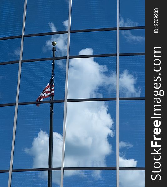 Flagmire - the observed reflection in a glass building of an American Flag twisted around its own flagpole in an attempt to display its colors, venetian blinds visible inside the building