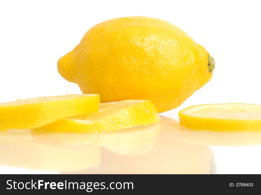 A lemon and lemon slices reflecting in white. A lemon and lemon slices reflecting in white.