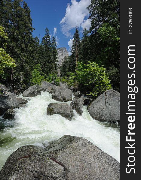 Mountain river, big stones, forest and blue cloudy sky on a sunny day in Yosemite National Park. Mountain river, big stones, forest and blue cloudy sky on a sunny day in Yosemite National Park