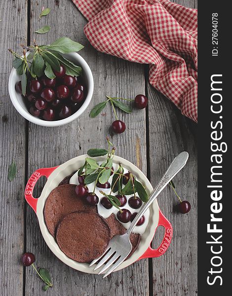 Chocolate pancakes with fresh cherries and vanilla sour cream in a bowl