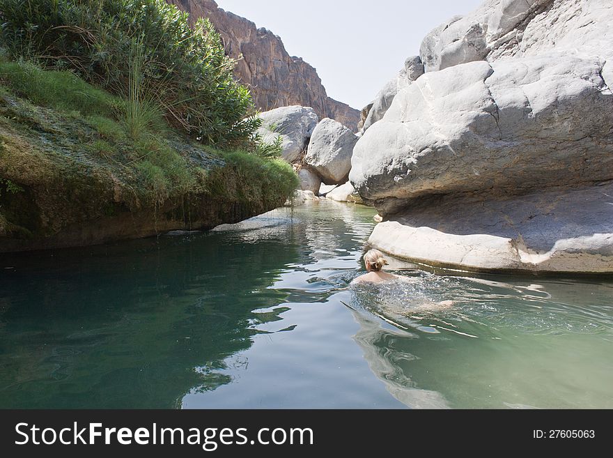 A women swimming in a rock pool in Wadi Damm located in Oman, Middle East. A women swimming in a rock pool in Wadi Damm located in Oman, Middle East.
