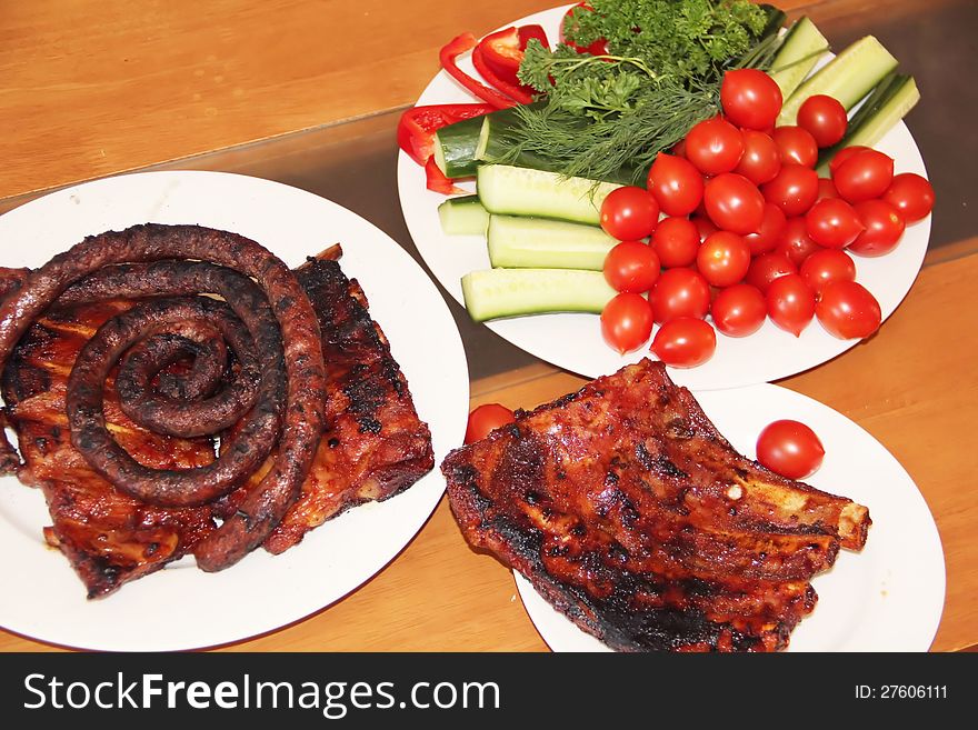 Grilled ribs and sausages with vegetables on the table