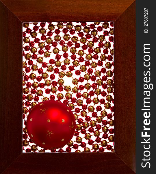 Christmas decoration, a ball of red-orange color in a rectangular wooden frame. The space inside the frame is filled with balls of red and yellow-gold color.