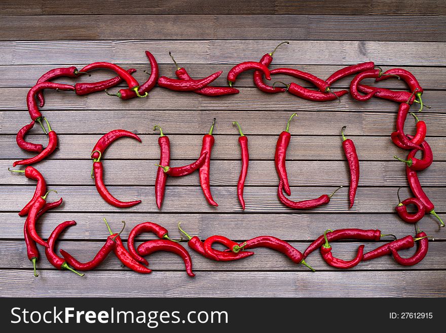 The word Chili on a brown table from hot red peppers of Chile