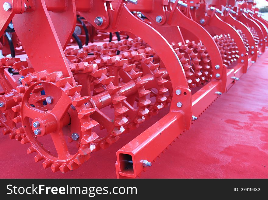 Detail of red agricultural equipment with toothed wheels.Red giant farming plough