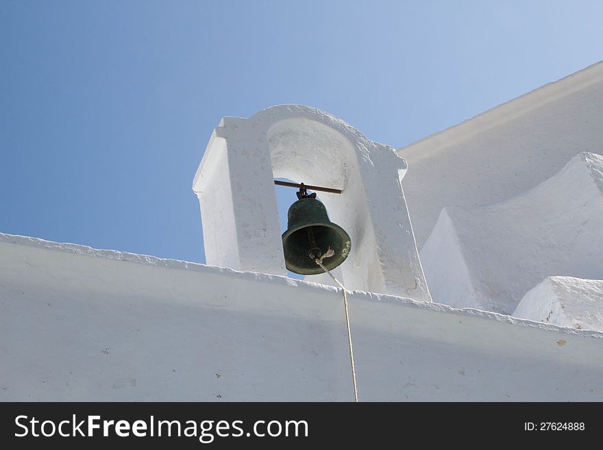 Church bell in small tower on roof of white church on the island of Milos, Greece.