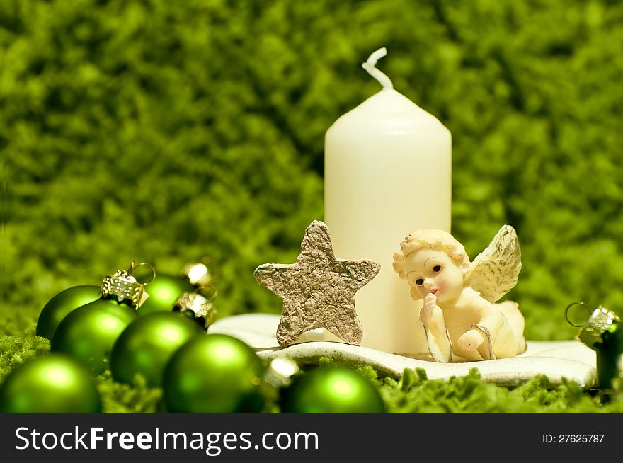 White candle and green christmas ornaments on green background. White candle and green christmas ornaments on green background