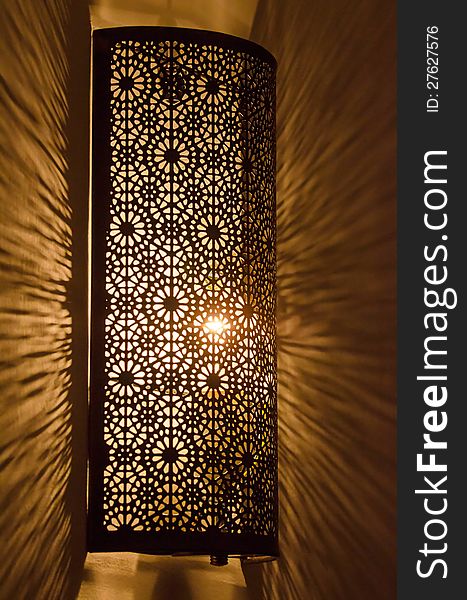 Ornate metal lamp glowing on wall. Ornate metal lamp glowing on wall