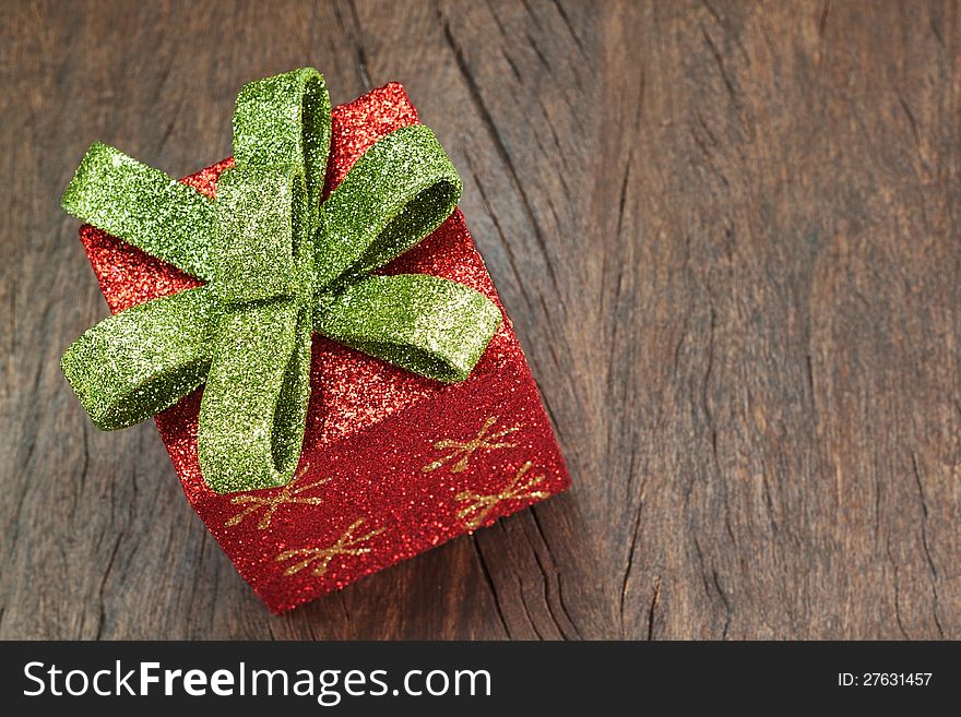Christmas gift box with a bow on a wooden texture closeup.
